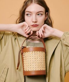 【allureville 2025 spring&summer】<br><br>イタリアのベネチア地方の椅子の座面に使用されるラタン素材を使ったバケットバッグ。著名デザイナーの作品にも使われる素材だそうです。椅子等のインテリアに使われる素材だけあって強度の強さもある素材だそう。<br>硬さのあるラタンを編み込み、サークル柄が連なっているように見える網目がとても美しく、レザーとの組み合わせでよりモダンに仕上がっています。<br>ショルダーを使って頂く際に、トップハンドルを前に倒してお使い頂く事もできます。<br><br><br>※照明の関係により、実際よりも色味が違って見える場合がございます。<br>またパソコン・スマートフォンなどの環境により、製品と画像のカラーが異なる場合もございます。<br>予めご了承ください。