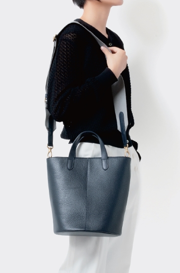 2WAYバケツ型バッグ。環境的・社会的コンプライアンスを高い基準でクリアし、環境保護や地域保全活動への影響を国際基準で審査する団体＜LWG（Leather Working Group）＞の認証を受けた、『サステナシュリンクレザー』を使用しています。均等なシボ感が特徴。裏地の生地はリサイクルポリエステルを使用。サイズ：H26 x W21 x D16cm 日本製。