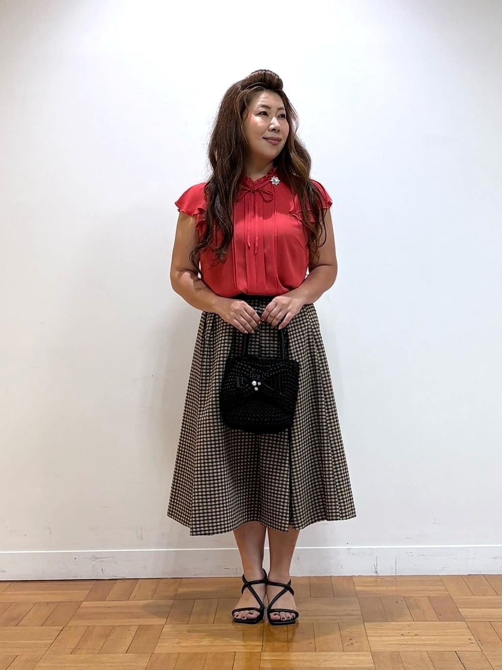 店頭でも好評のギンガムスカートは夏らしい鮮やかなオレンジのブラウスと合わせてみました。ブラウスは首元や袖口のデザインがオシャレで涼しくお召しいただけます。【モデル身長：158cm】