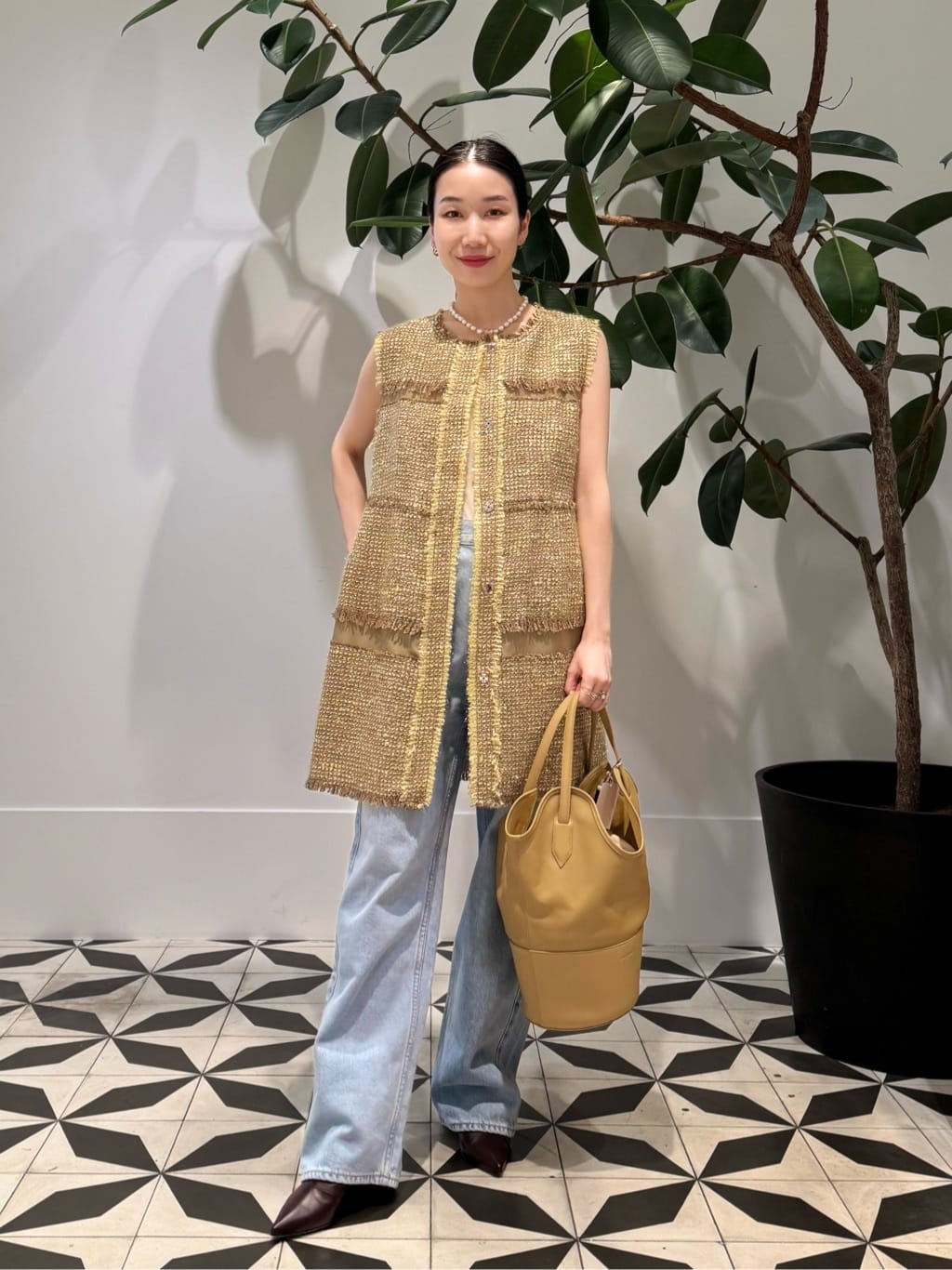 身長158㎝　フリンジのあしらいが目を惹く、ツイード素材のロングジレを主役にしたスタイリング。

ゴールドを織り込んだツイードは、光の加減で表情を変え、華やかさと品のある存在感を放ちます。インナーにはシンプルにベロアキャミソールを合わせ、ジレの繊細な素材感を際立たせました。

ボトムは淡いブルーのデニムを選び、カジュアルな軽やかさをプラス。
太めのシルエットが、ロングジレと好バランスを作り出しています。足元はシャープなトゥのブーツでまとめ、全体をきりりと引き締めました。