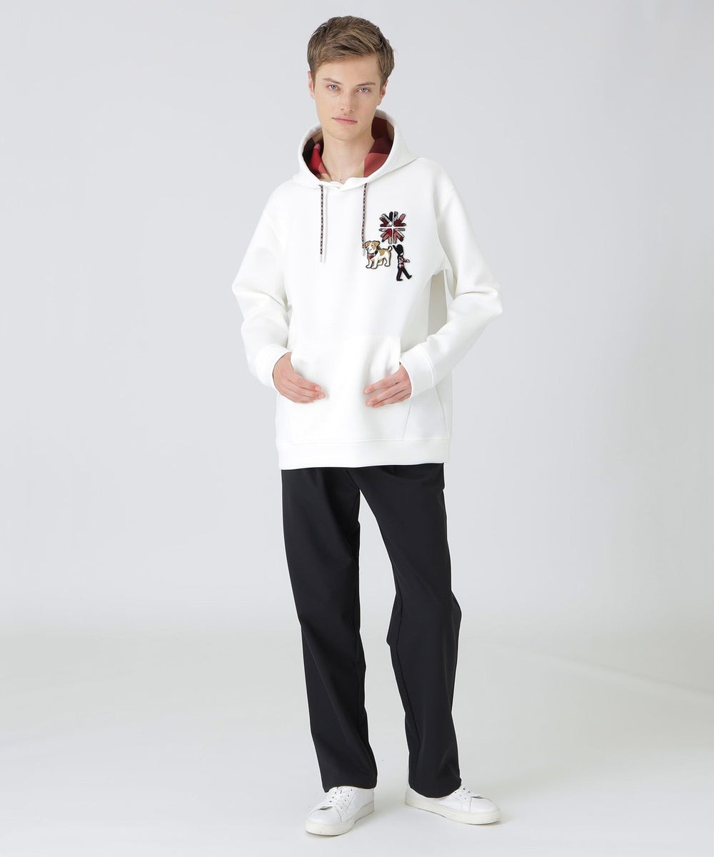 左胸にワッペンをあしらったダンボールニットフーディー。イギリスを象徴する「ユニオンジャック」や「ガーズマン(衛兵)」、イギリス原産の犬「ジャックラッセルテリア」をモチーフにアイコニックなクレストブリッジチェック柄を掛け合わせた遊び心あるデザインが特徴です。