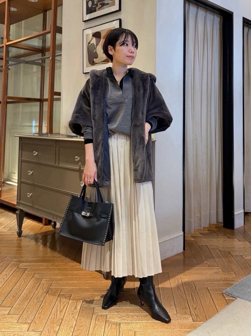 身長156㎝　オープンカラーのニットは、程よい抜け感とレイヤードスタイルを楽しめる一枚。
同シリーズのニットを重ねて奥行きを出し、モノトーンでまとめることで上品な印象に。
軽やかな着心地のエコファーポンチョは、やわらかなツヤ感があり、装いにさりげない華やかさを添えます。
動くたびに揺れるプリーツスカートが、冬の日差しに映える優しい温もり演出します。
