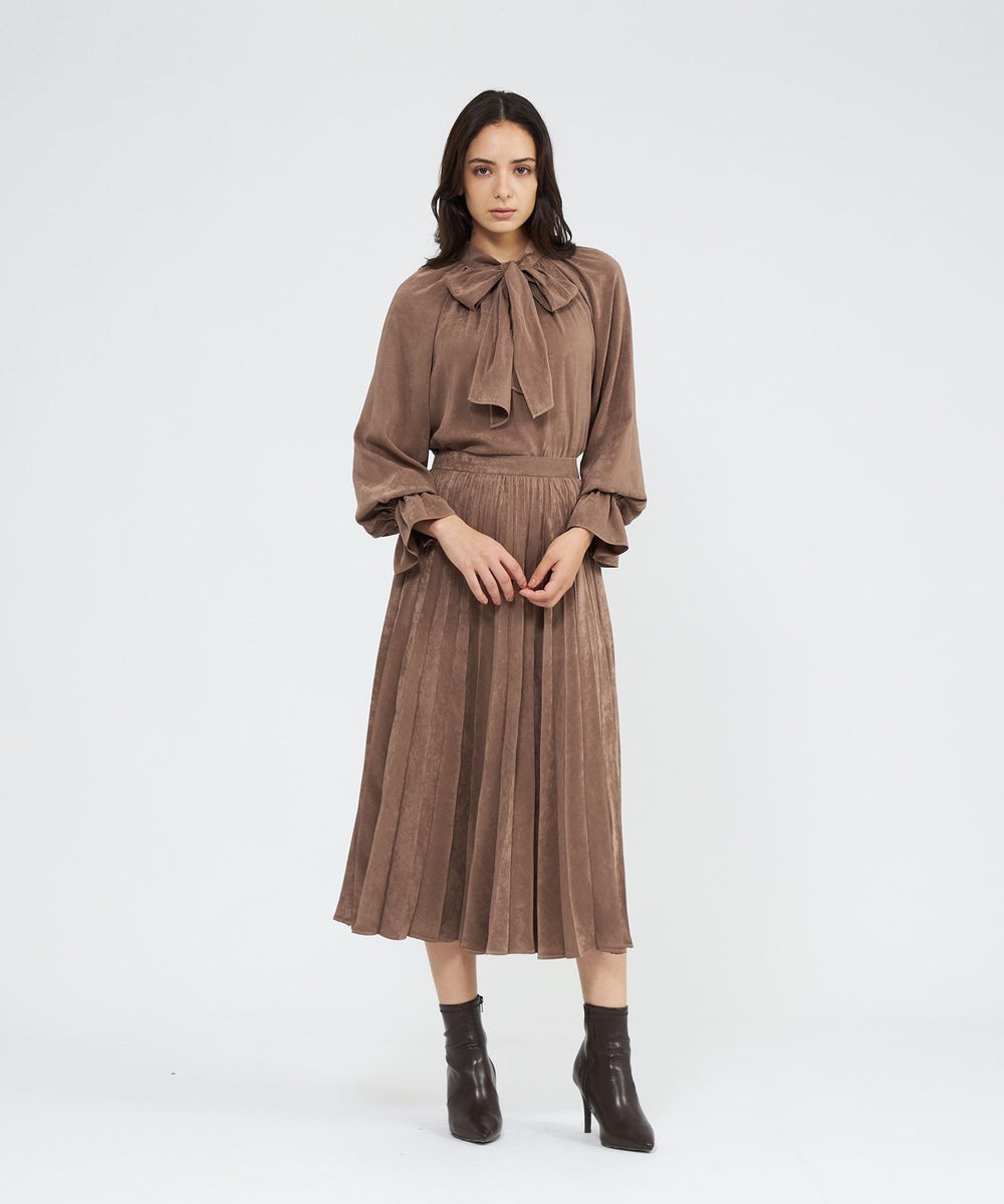 襟元のボウタイとベルスリーブが印象的なブラウス。スエード調のピーチタッチ素材が上品な印象で、袖のフリルも甘くなりすぎない仕上がりです。ボウタイは取り外し可能で、シンプルなスタンドカラーブラウスとしても着用できます。ご自宅で手洗い可能です。洗濯表示に従ってお手入れしてください。