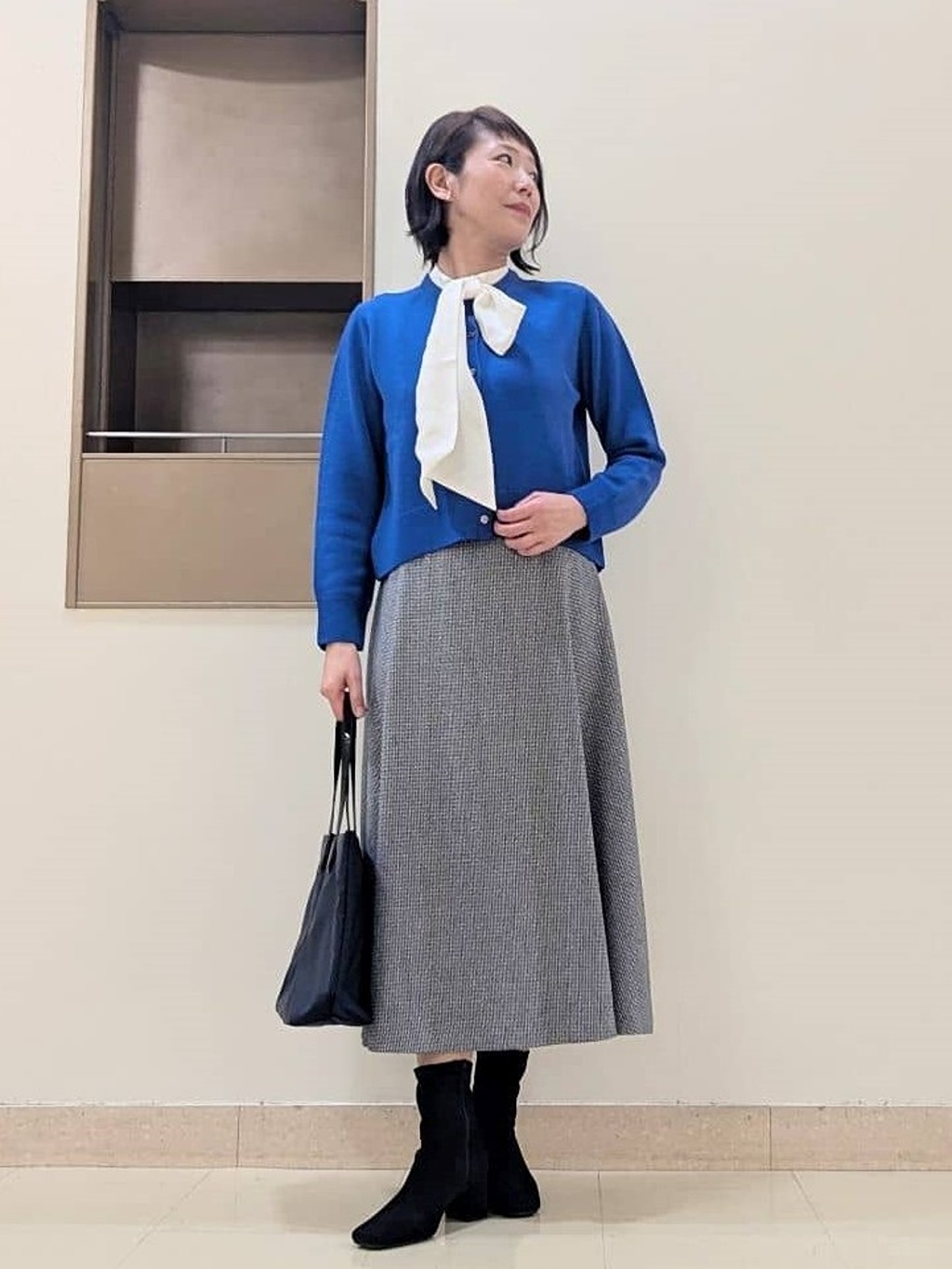 微光沢が上品なシルク混の丸首カーディガン。前身裾上がりですっきりとした印象に。重ね着風を楽しめるボウタイ付きのつけ襟をプラス。裾にかけて広がる美しいフレアラインのスカートは、後ろギャザーでストレスフリー。上品な冬のお出掛けスタイルにまとめました【モデル身長：163cm】