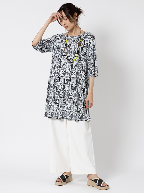 ポップな手描き風のフラワーモチーフをあえてシックなワントーンで表現したチュニックをシロのワイドパンツを合わせたコーディネートです。一見するとシンプルなAラインシルエットですが、実は切り替えやダーツの位置を細かく計算し、立体的に仕立てているため、シュッと細見えするようなシルエットが生まれます。
モデル身長：165cm