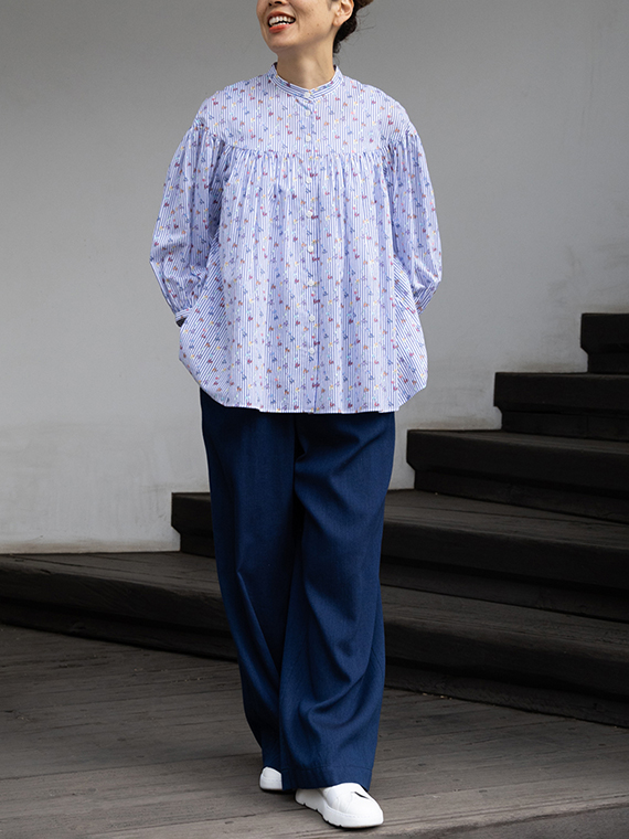 胸元の大きなヨーク切り替えから贅沢に広がるギャザーが特徴のプリントブラウスをインディゴ染めのワイドパンツと合わせた若々しいコーディネートです。ブラウスは身頃にも袖口にもたっぷりとボリュームを持たせているので、動くたびに空気をはらんで、ふんわりと優雅なシルエットを描きます。
モデル身長：162cm