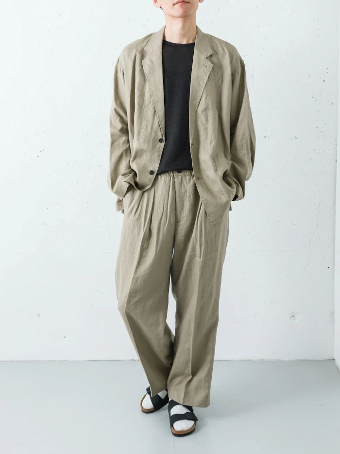 ベージュのリネンシャツジャケットとワイドパンツを合わせた、季節感あふれるセットアップスタイルです。
リネン特有の軽やかな風合いと、ベージュの柔らかなトーンを活かしつつ、インナーにブラックのトリムTシャツを合わせることで、全体を都会的に引き締めています。