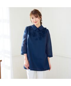 程よくゆとりのあるサイズ感が気になる体型をカバーしてくれるＡラインシルエットのブラウス。<br>胸元には異素材使いの花モチーフをあしらい、１枚で着映えできるデザインに。<br>程よくハリ感と厚みのあるオーガンジーを使用しているので着るだけで立体的なシルエットを出してくれる、1枚で着映えるアイテム。<br>襟はボタンで取り外しできるので、シンプルに丸首のプルオーバーとしても着用可能。<br>リボンの引き手が着脱しやすい背中ファスナー開き。<br>オフホワイト、ピンク、ネイビーの全3色。<br><br>************************************<br>生地感: 普通<br>伸縮性: なし<br>透け感: なし<br>裏　地: 袖のみ裏なし<br>洗　濯: ドライクリーニング<br>************************************<br>モデル身長: 166cm/ 38号着用<br>詳細着用モデル身長　161cm / 着用サイズ 38号<br><br>＊取り扱いについては、商品についている品質表示でご確認ください。<br>＊撮影環境により、実際と色味が違って見える場合があります。<br>また、PC・スマートフォンなどにより、製品と画像のカラーが異なる場合もございます。<br>＊商品画像はサンプルのため、色味やサイズ、プリント位置、仕様などに変更がある場合があります。<br>＊50号は一部の店舗・ONLINE SHOPのみの展開となります。取扱いしていないサイトもございますのでご了承ください。<br><br><br><br><font color='#e73656'>【RoseTiara/ローズティアラ】</font><br>フェミニンな愛らしさと、大人のエレガンスを一度にまとう服。 <br>「可愛い」をずっと手放さない、あなたのためのブランドです。<br><br>素材選びからデザイン、パターンまでを一貫して行い、タックの向きやギャザー分量、フリル位置などを36・38・40号と42・46・50号では調整し、パターンを分けることで美しいシルエットと着心地の良い服を提案します。<BR>